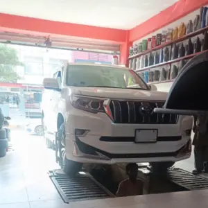 White SUV on lift in auto workshop with mechanic underneath.